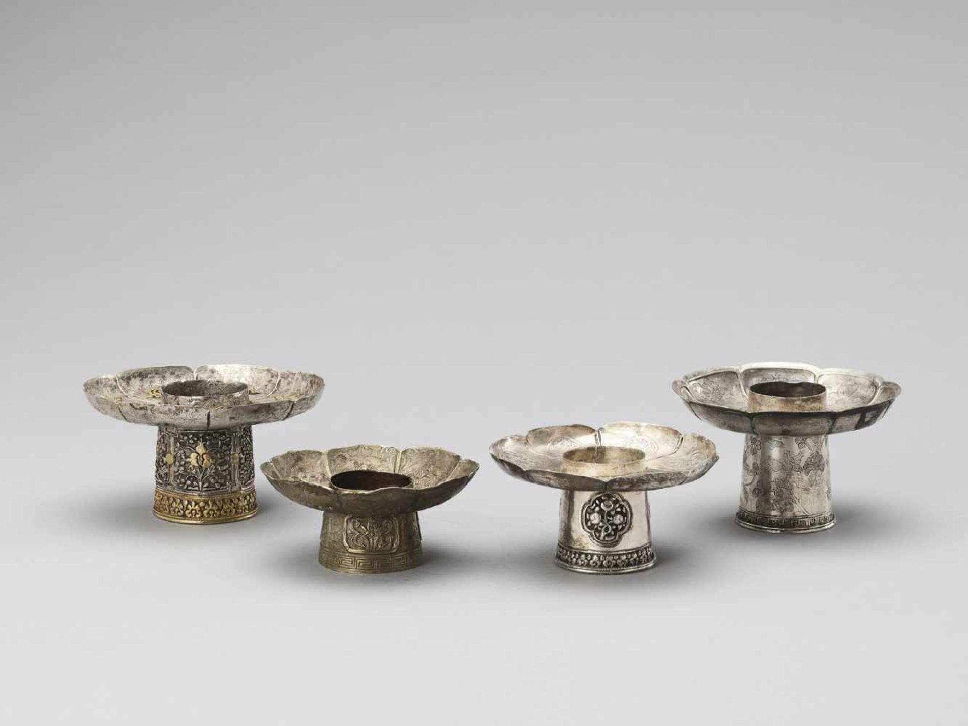 FOUR SINO-TIBETAN SILVER PARCEL-GILT ‘BAJIXIANG’ CANDLE HOLDERS, QING <br