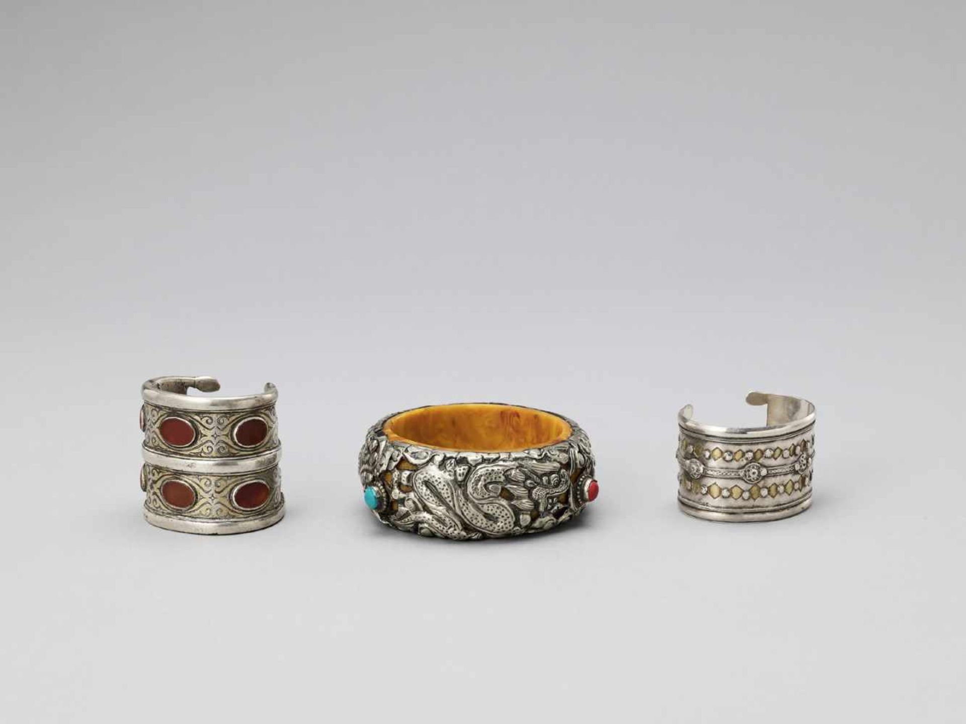 THREE PARCEL-GILT AND GEMSTONE-INLAID SILVER BANGLES, LATE 19TH TO EARLY 20TH CENTURY