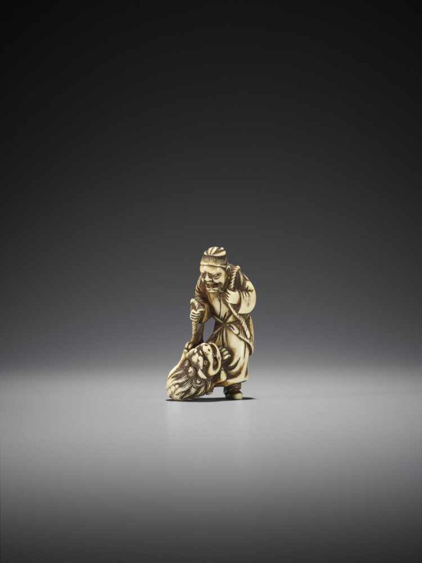 A RARE IVORY NETSUKE OF A CHINESE SAGE WITH SHISHI