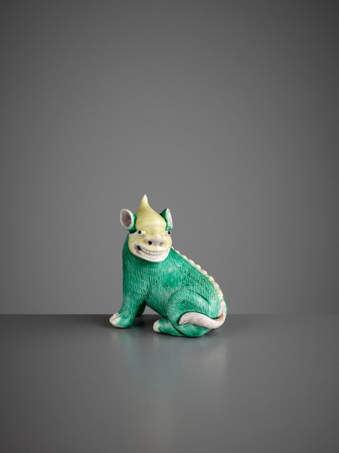 A SMALL BISCUIT FIGURE OF A RECUMBENT QILIN, KANGXI