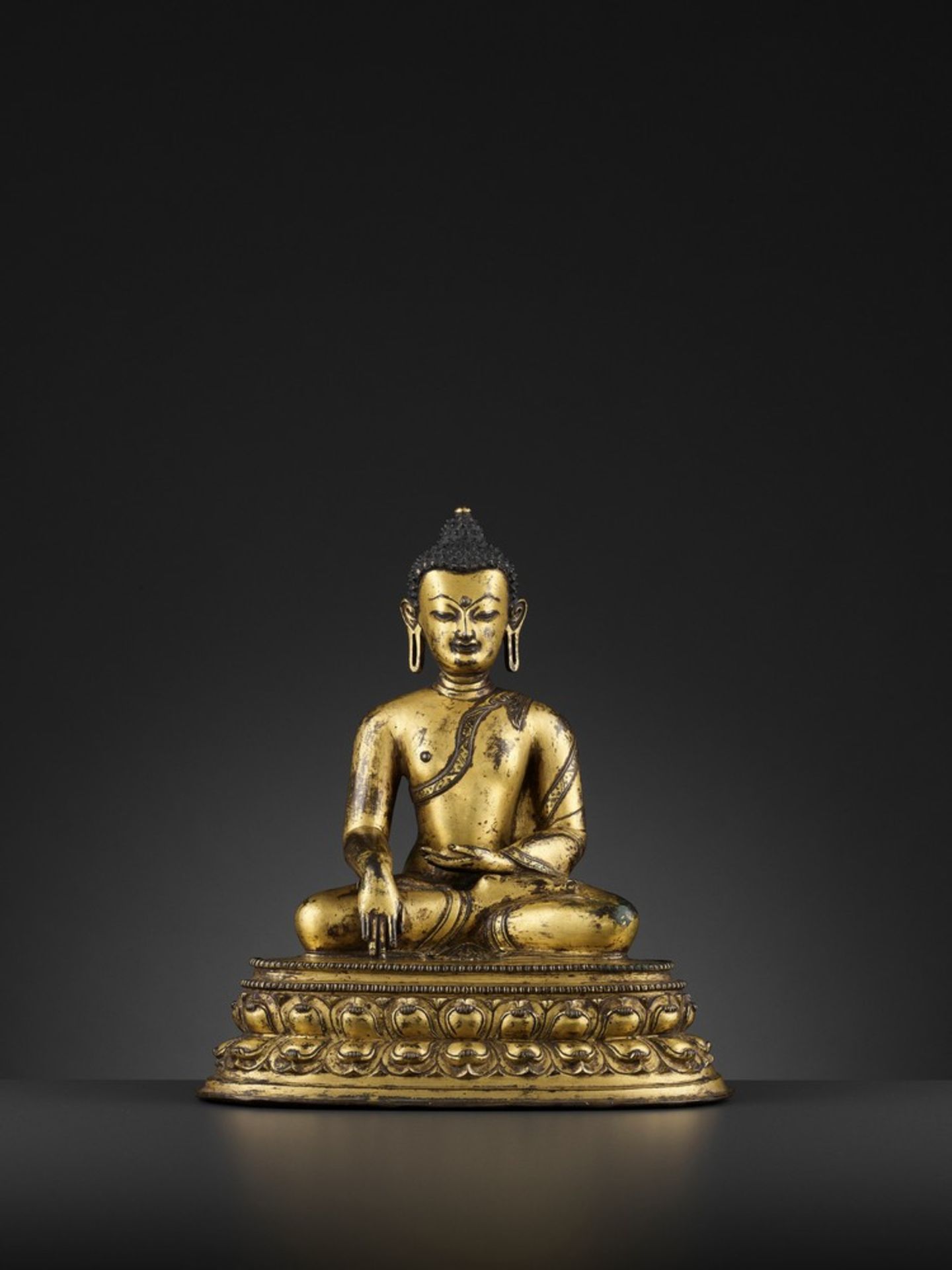 A LARGE GILT BRONZE FIGURE OF SHAKYAMUNI BUDDHA, TIBET, 15TH CENTURY