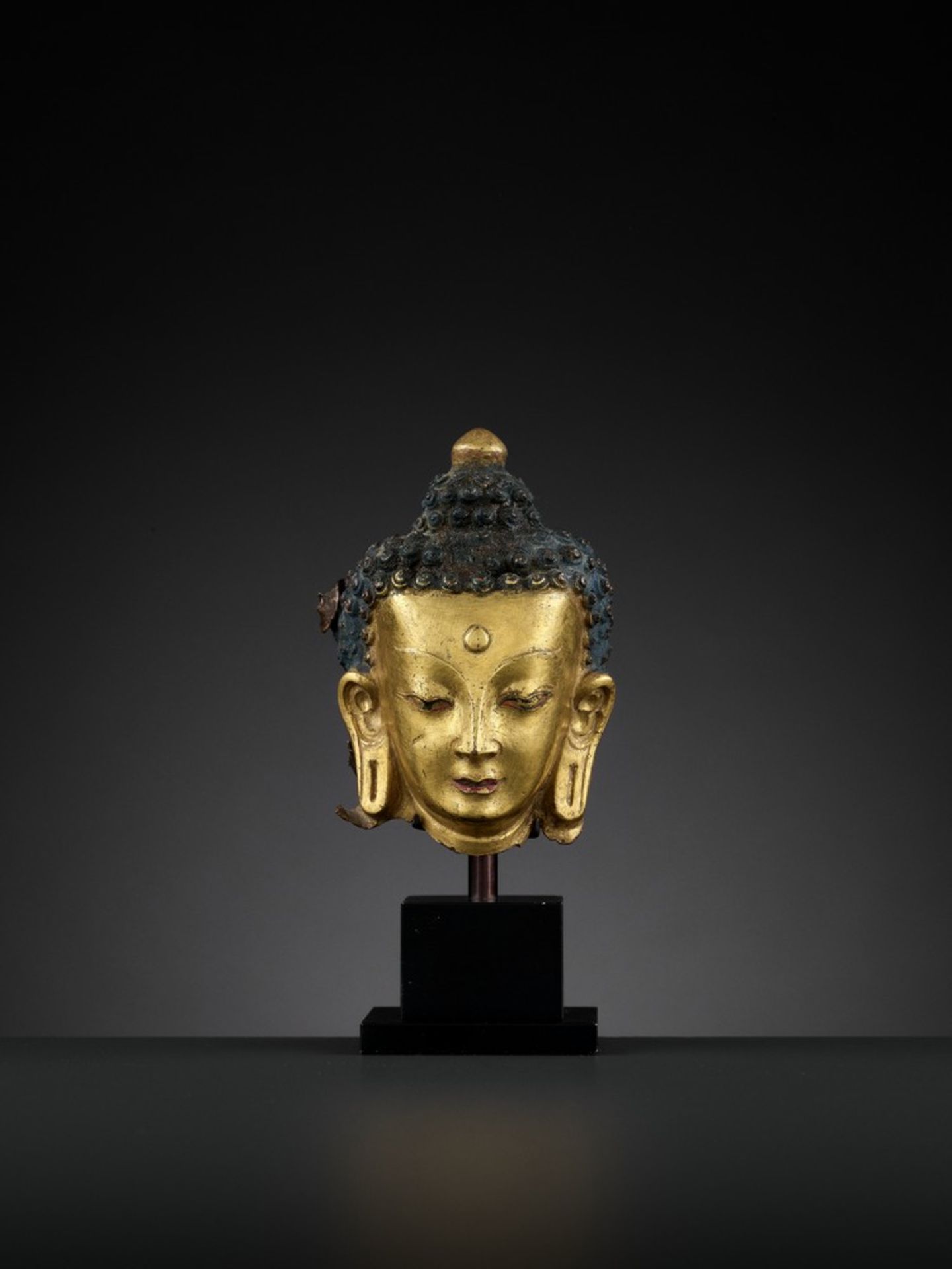 A GILT COPPER REPOUSSÉ HEAD OF BUDDHA, 18TH CENTURY <