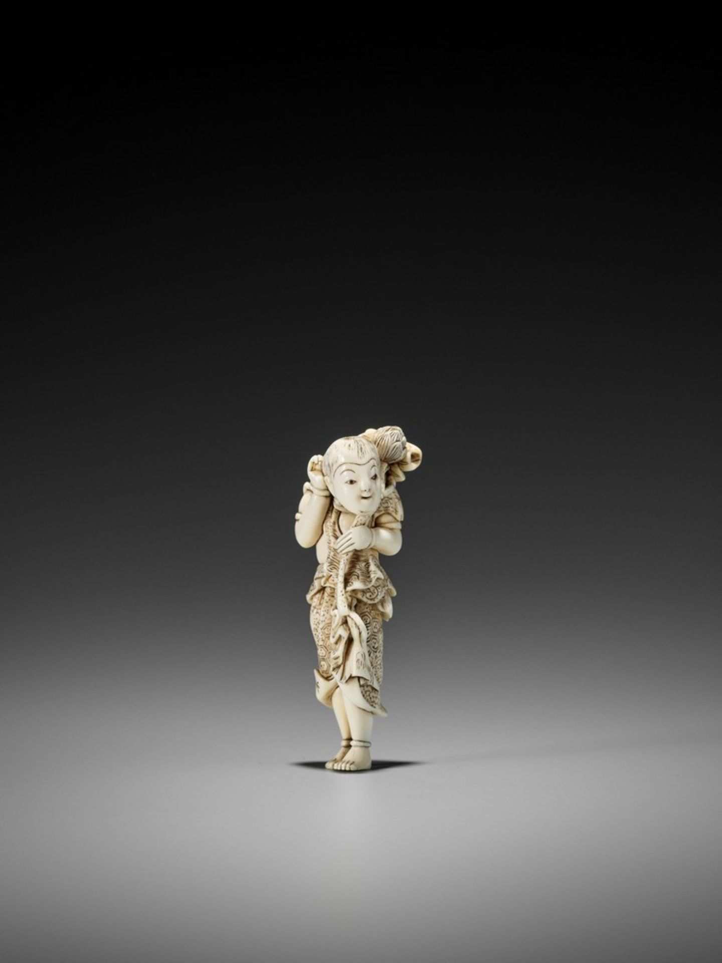 SHUYO: A RARE IVORY NETSUKE OF A BOY HOLDING A LOTUS FLOWER By Shuyo, signed Shuyo 秀予Japan, early