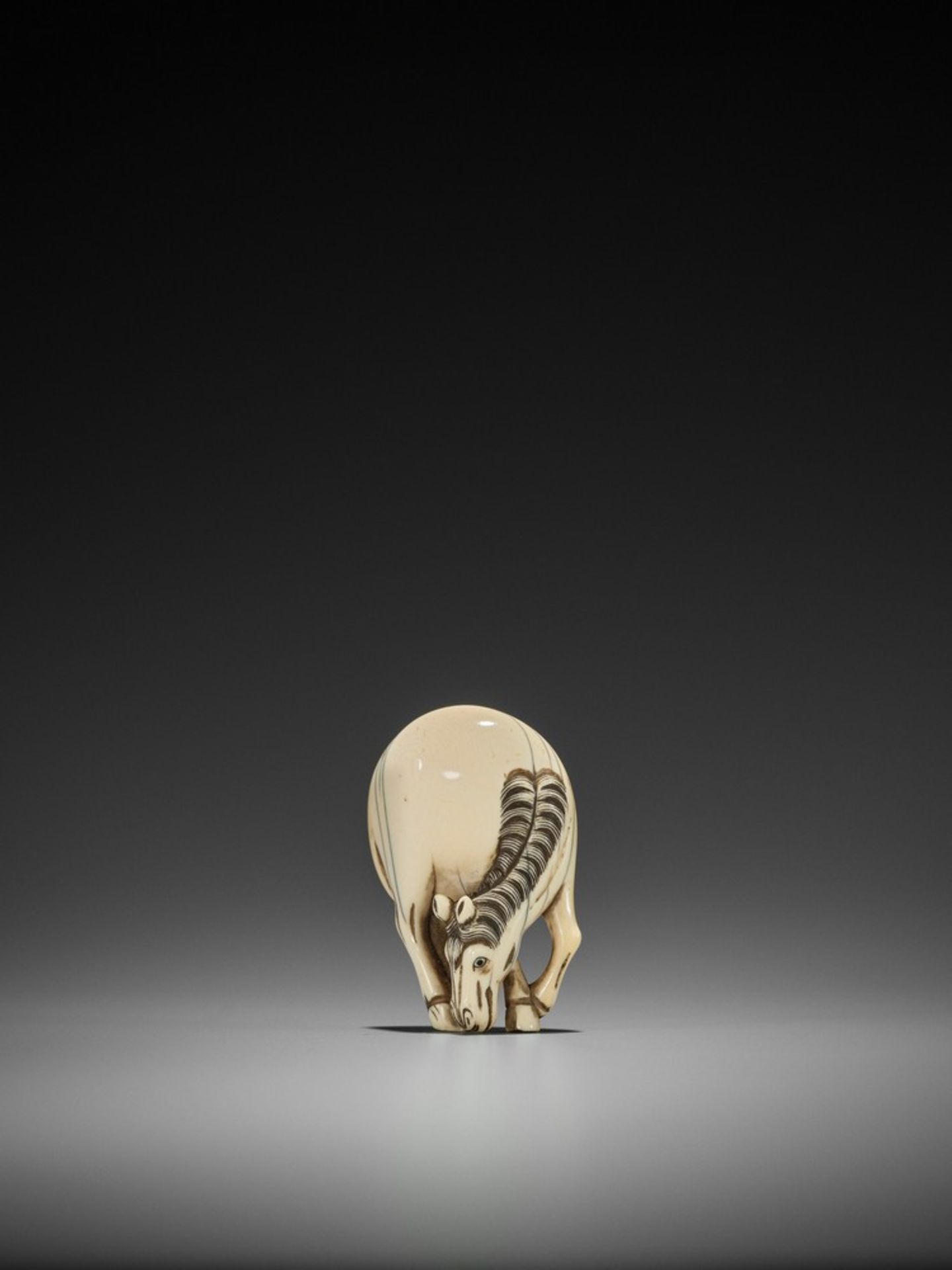 KANO TESSAI: A RARE IVORY NETSUKE OF AN 18th CENTURY GRAZING HORSE By Kano Tessai (1845-1925),