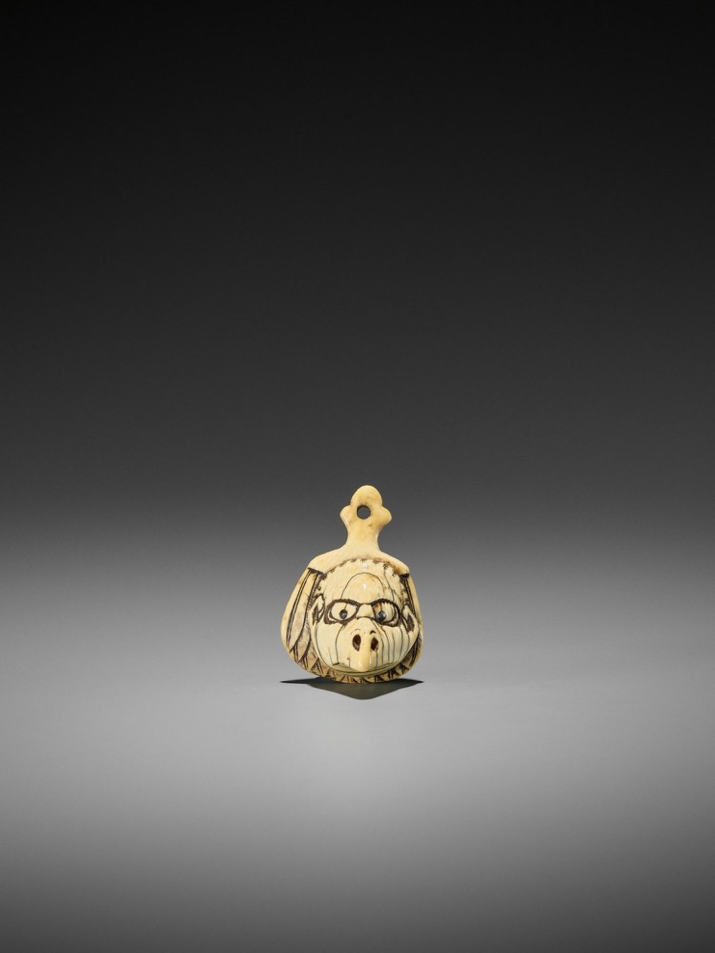 AN IVORY NETSUKE OF A TENGU MASK ON A FEATHERED FAN UnsignedJapan, late 18th to early 19th