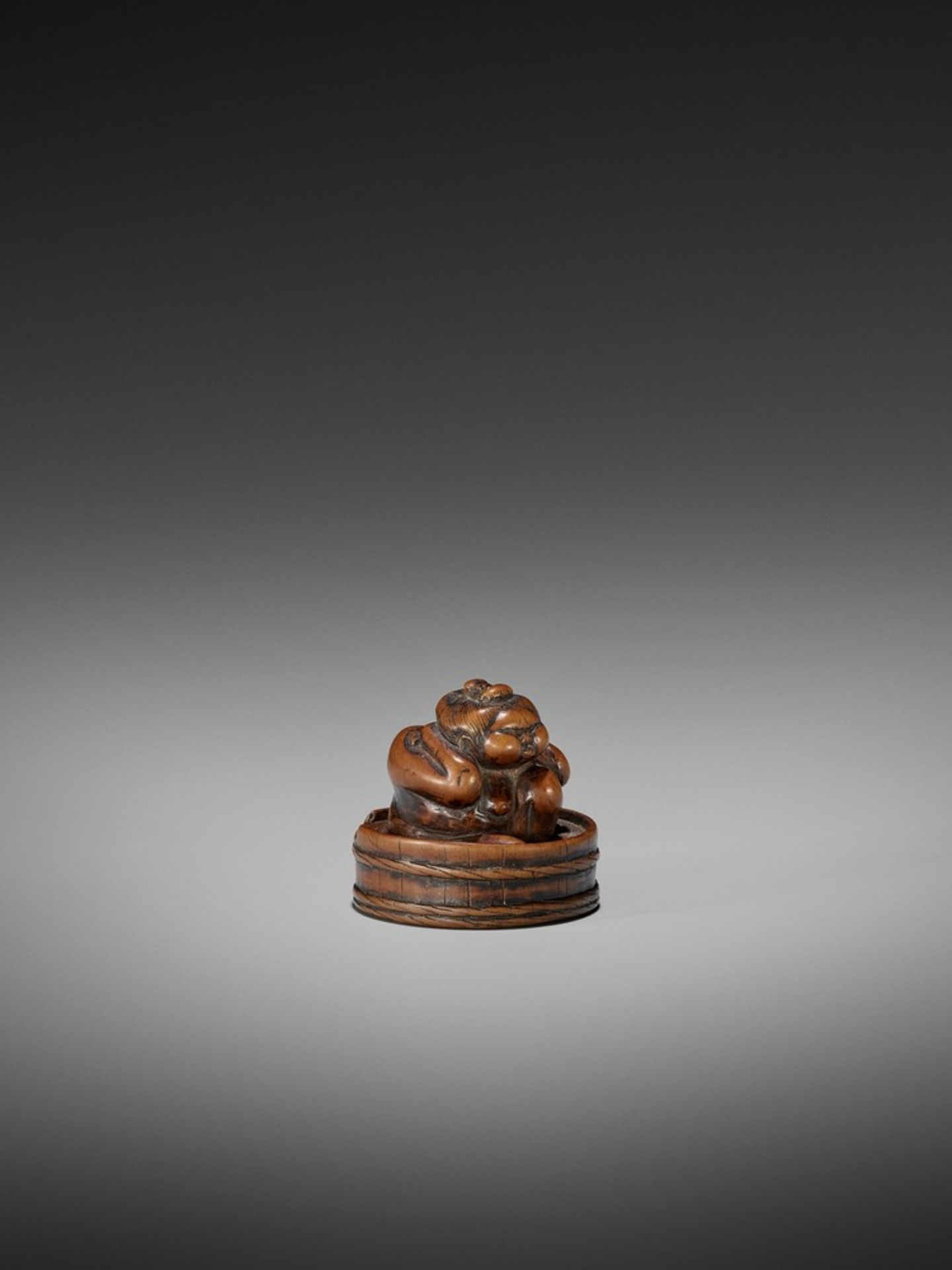 AN EARLY WOOD NETSUKE OF OKAME IN A BATHTUB UnsignedJapan, 18th century, Edo period (1615-1868)The