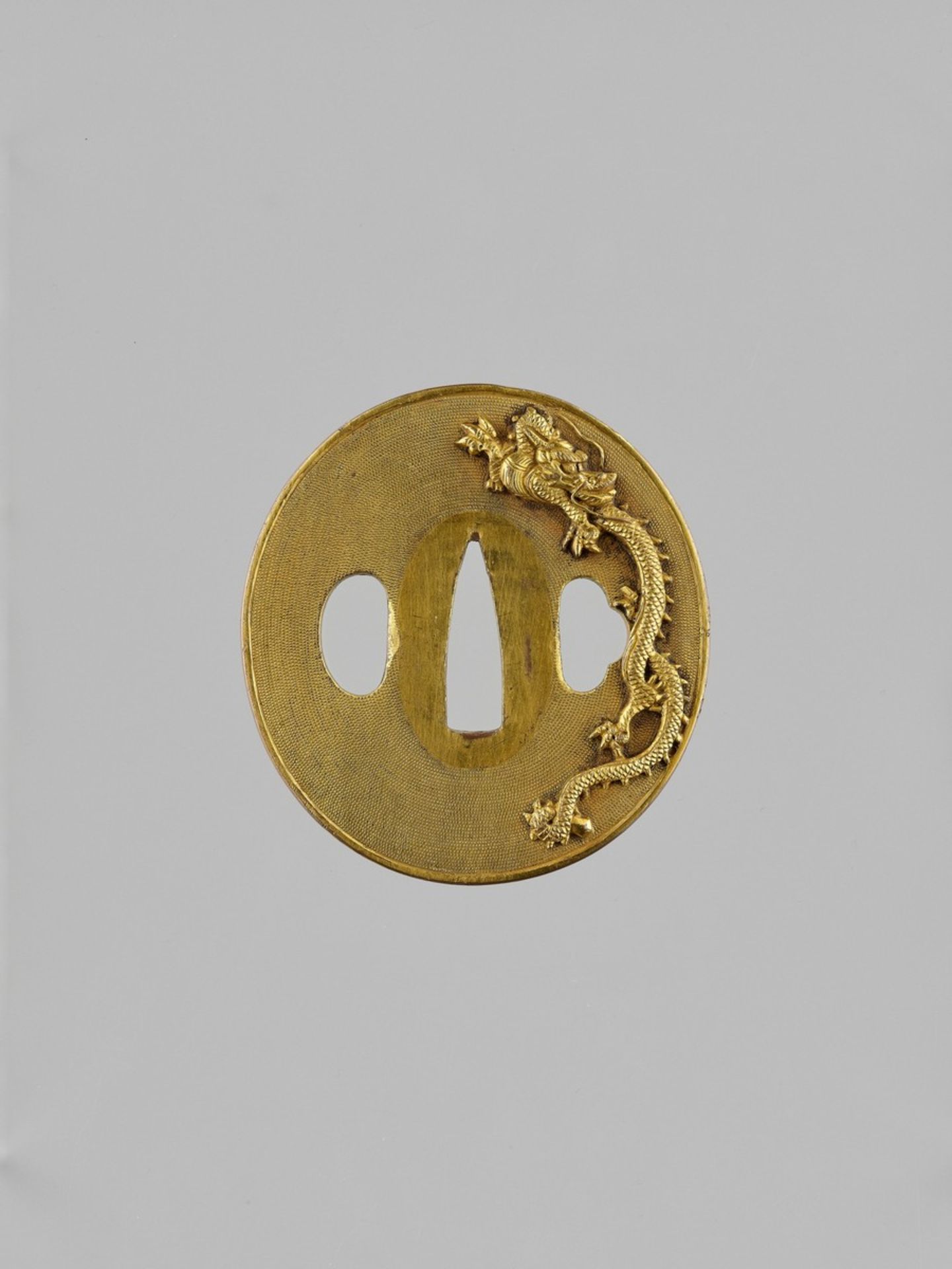 AN IMPRESSIVE GILT COPPER TSUBA WITH DRAGONS Japan, 19th century, Edo period (1615-1868)The heavy