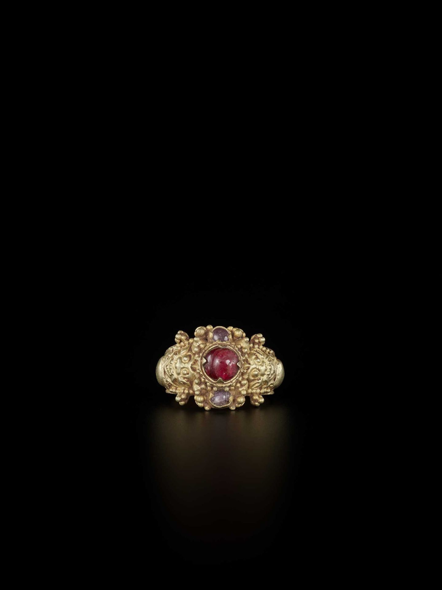 A CHAM RUBY AND AMETHYST-SET GOLD REPOUSSÉ RING WITH KALA MASKS