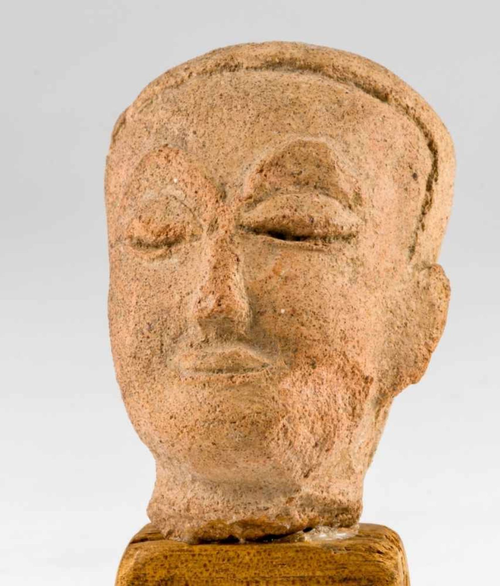 Head of Buddha, South-East-Asia, stone, probably 18/19th c., 7,5 x 5,5 x 5 cm (without thewodden