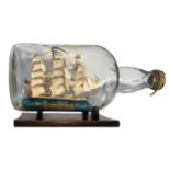 Sailing ship in a glass bottle, with a wooden base. 20th century. Cm 20x37.