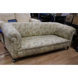 A mid 20th century chesterfield style sofa, raised on turned supports on brass castors