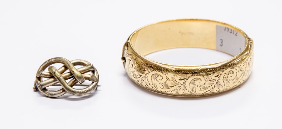 A rolled gold hinged bangle with engraving, along with a Victorian white metal lovers knot brooch (