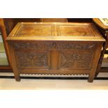A 17th Century and later carved grained oak blanket chest, two panels with floral carving, raised on