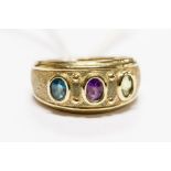 A three stone set ring, set with oval cut amethyst, blue topaz and peridot cabochons, rubover set to