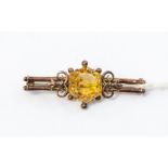 A 9ct gold and citrine bar brooch, the stone set centrally set stone, scroll decoration, total gross
