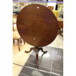 A George III mahogany tilt top table, circa 1800, on a turned column raised on saber tripod legs.