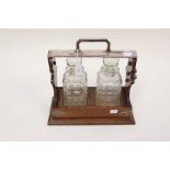 An early 20th Century oak tantalus, fitted with two square cut glass decanters, complete with a