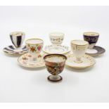 A collection of five unusual early 19th Century Derby egg cups on stands, various decoration,