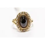 A 19th Century garnet and seed pearl ring, comprising a central cabochon garnet inset within a