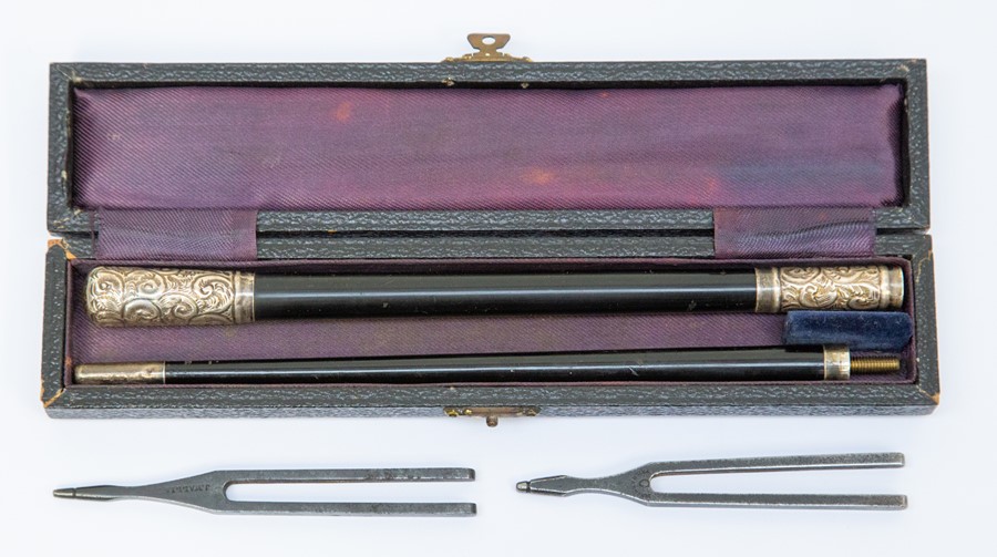 An ebonised conductor's baton, with white metal mounts engraved with foliate scrolls, cased; with