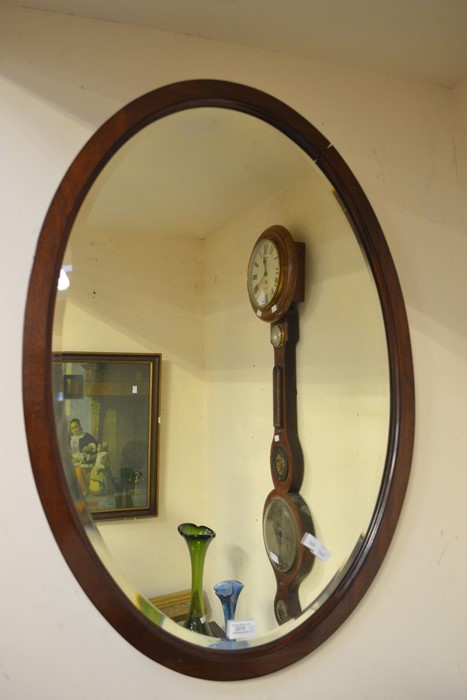 An oval mahogany wall mirror in the Victorian style along with an ornate brass-framed mirror