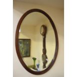 An oval mahogany wall mirror in the Victorian style along with an ornate brass-framed mirror