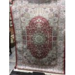 A contemporary Keshan design woollen rug, machine made, symmetrical foliage pattern on a red ground,