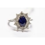 A sapphire and diamond 9ct white gold cluster ring, oval diamond with claw set diamond border,