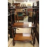 A Victorian rosewood three tier whatnot, of serpentine form, raised on barley twist supports, turned