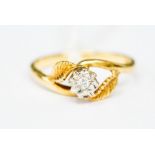 An 18ct gold and diamond solitaire ring, the illusion-set stone flanked by two leaves to