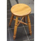 An early 20th century elm stool on turned supports and stretchers.