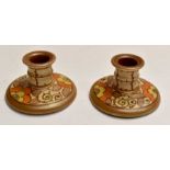 A pair of Charlotte Rhead Bursley Ware squat candlesticks, Art Deco, hand painted throughout with
