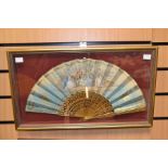 A Victorian hand painted fan, depicting an 18th Century courting couple, presented in a framed case,