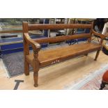 An early 20th century oak settle on turned supports
