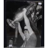 A signed black and white press photograph of Emlyn Hughes, after Liverpool won the European Cup in