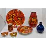 A collection of seven items including Poole Pottery, three vases and four dishes, orange and red
