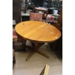 A 20th Century grained pine table, circular top supported on a turned column on x-shaped feet