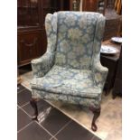 A George III style wing back chair c. 1920, shell carved legs terminating in pad feet, upholstered.