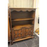 A 20th Century oak open bookcase, rectangular top above two tier shelving on two panel cupboard