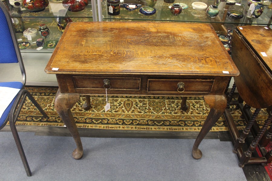 A George II oak and mahogany cross banded side table, fitted with two drawers, cabriole legs