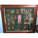 A framed collection of 22 wire bullion shooting badges and 6 bronze medallions awarded between