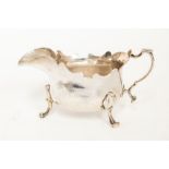 A George II Provincial silver plain squat sauceboat, cut card border above three scroll and