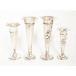 A matched pair of Edwardian graduated silver trumpet shaped vases, bodies chased with Iris, by