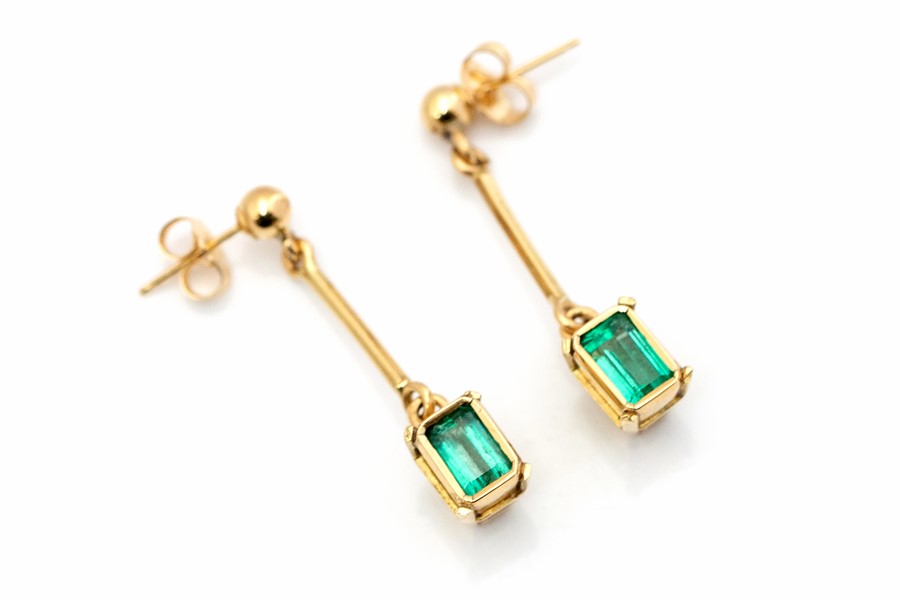 A pair of emerald and yellow gold drop earrings, comprising rub-over set emerald-cut emeralds,