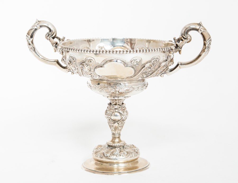 An Edwardian silver two handled cup on stand, the ogee bowl with beaded rim above S scroll floral