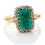 An emerald and diamond  rectangular cluster ring, the central rectangular step cut emerald