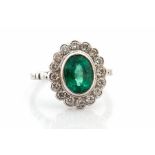 An emerald and diamond platinum cluster ring, the collet set oval-cut emerald approx 1.96 carats,
