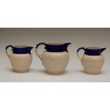 A graduated set of Chetham and Woolley feldspathic stoneware jugs with blue rims, circa 1810. Each