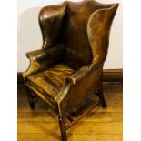 A George III brown leather wingback armchair, circa 1760, brass studs around the frame, scrolled