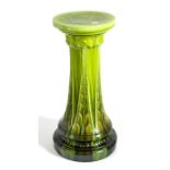 A Bretby Art Pottery jardiniere stand decorated with green glazes on moulded art nouveau repeating